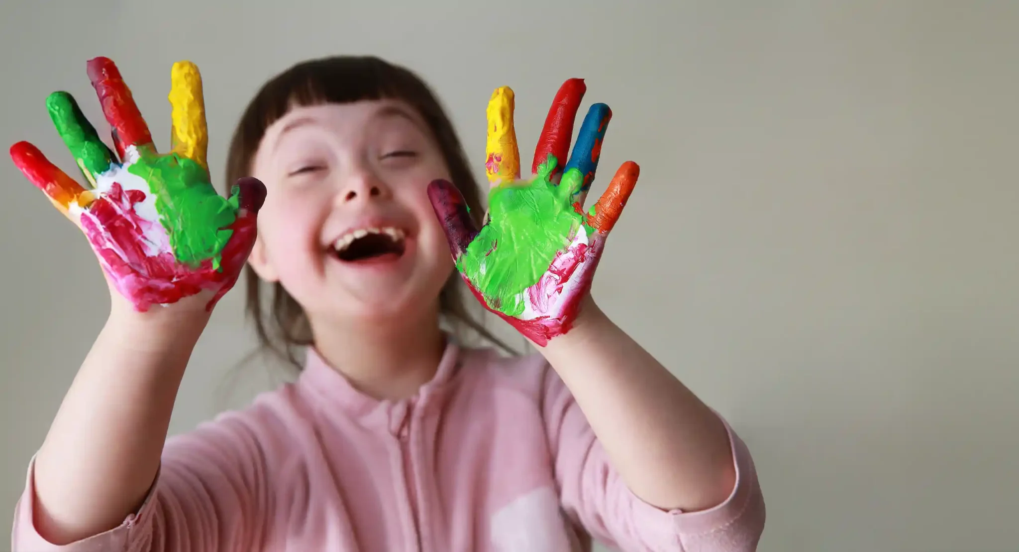Child joyfully showing colorful painted hand.